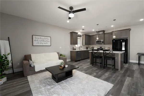 a living room with couches kitchen view and a refrigerator