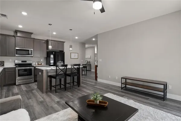 a living room with stainless steel appliances furniture and a kitchen view