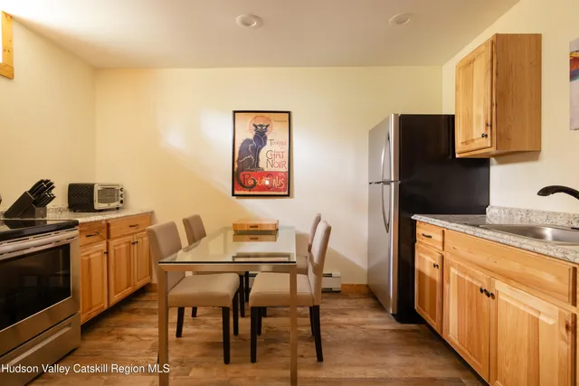 a kitchen with stainless steel appliances granite countertop a refrigerator a stove a sink a dining table and chairs with wooden floor