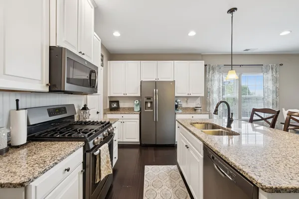 a kitchen with stainless steel appliances granite countertop a sink a stove a refrigerator a center island with wooden cabinets