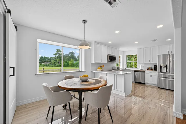 a kitchen with a dining table chairs and wooden floor