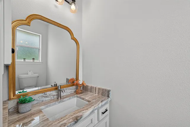 a bathroom with a granite countertop sink and a mirror