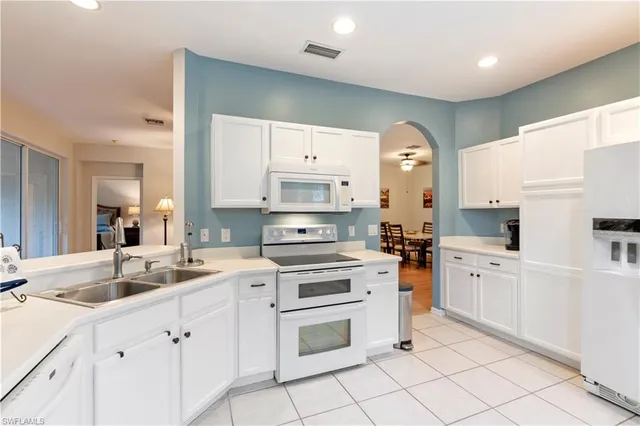 a kitchen with white cabinets and white appliances