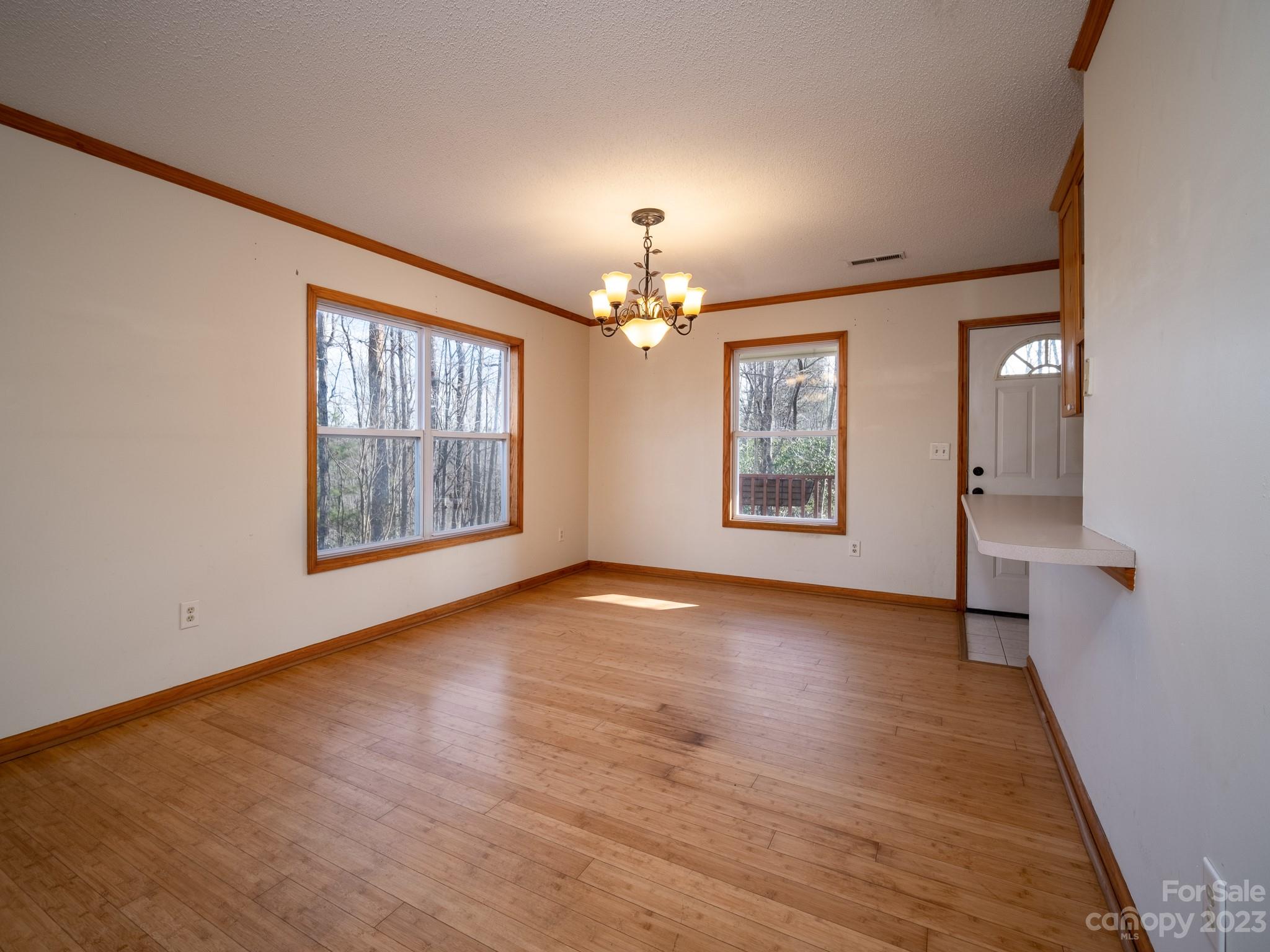 430 Jeep Road Brevard, NC 28712 - Photo 19 of 45 an empty room with wooden floor chandelier and windows