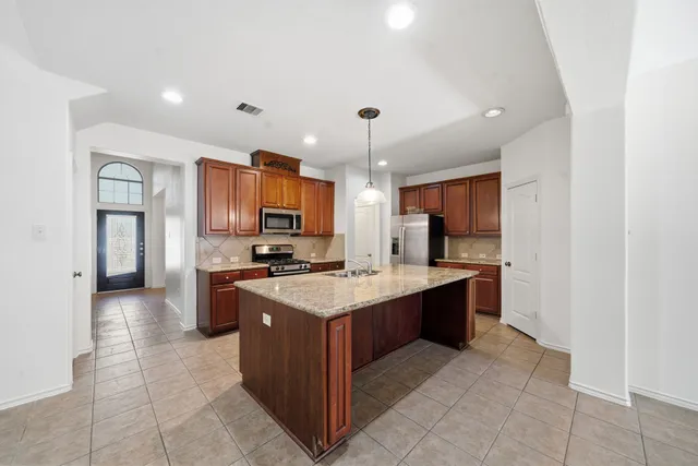 a large kitchen with stainless steel appliances a sink and cabinets
