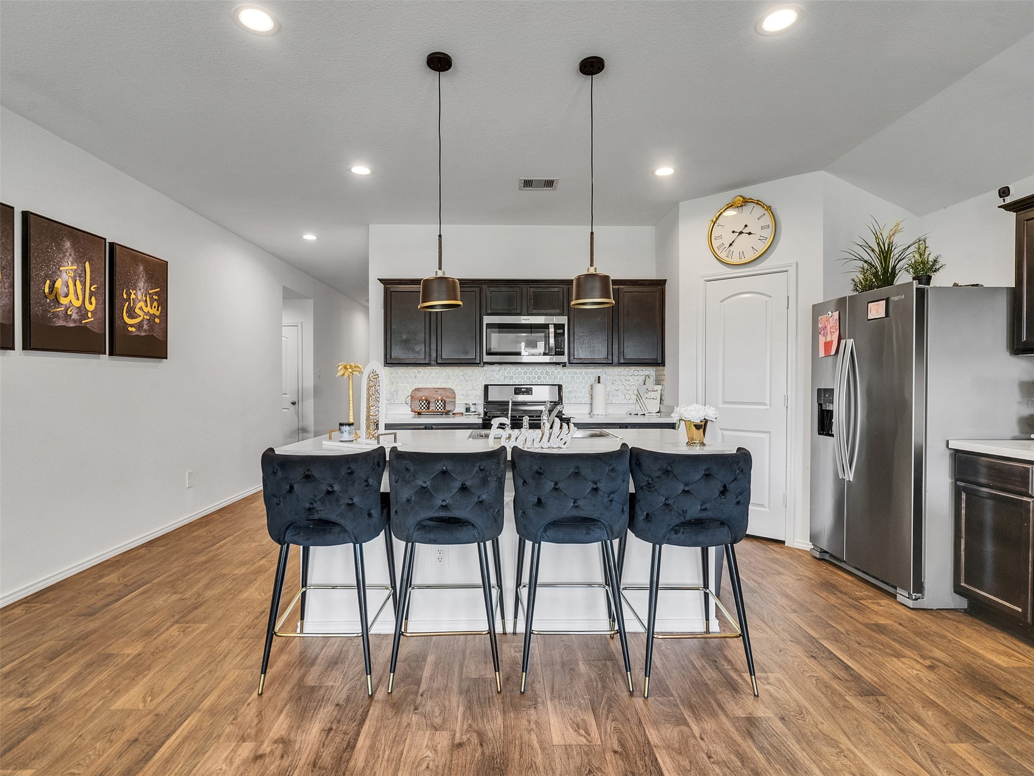 21215 Audubon Russet Road Katy, TX 77449 - Photo 13 of 30 a kitchen with stainless steel appliances granite countertop a stove top oven a refrigerator a dining table and chairs with wooden floor
