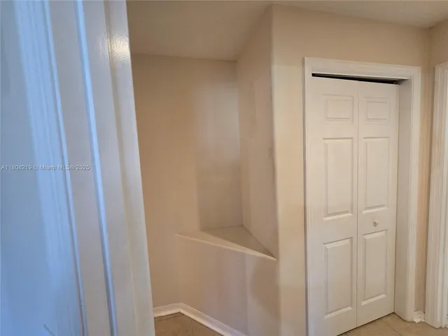 an empty room with windows and chandelier fan