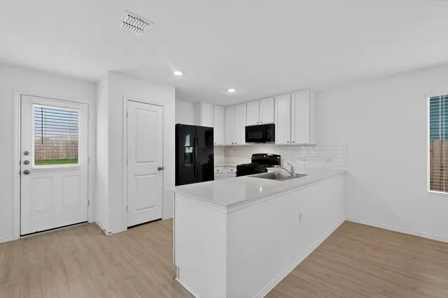 a view of kitchen with stainless steel appliances refrigerator stove microwave and cabinets