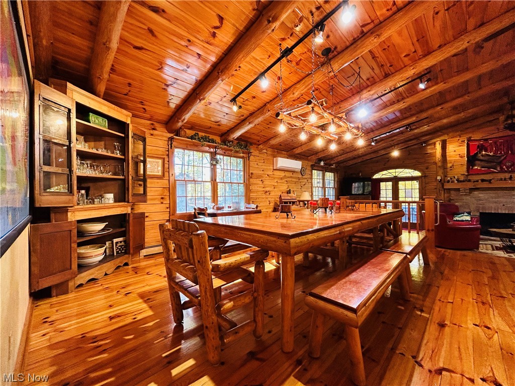 17367 Reeves Road Middlefield, OH 44062 - Photo 12 of 35 Dining room with vaulted ceiling with beams, wood walls, wood ceiling, an AC wall unit, and light wood-type flooring