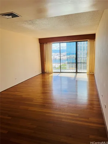 a view of an empty room with wooden floor and a window