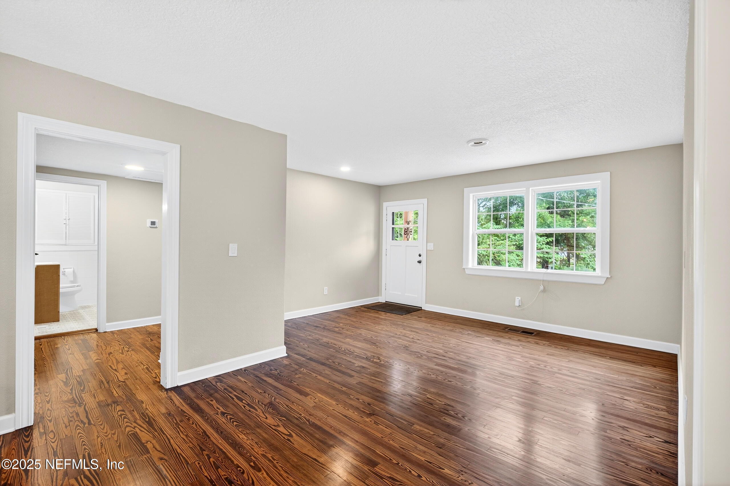 9906 Jeanette Road Jacksonville, FL 32246 - Photo 4 of 32 a view of an empty room with wooden floor and a window