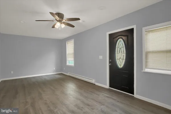 an empty room with wooden floor closet and windows
