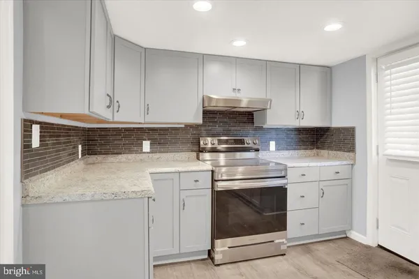 a kitchen with stainless steel appliances granite countertop a stove a sink and white cabinets