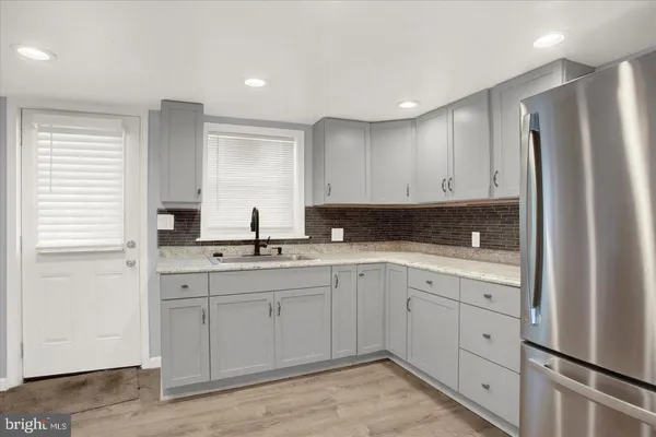 a kitchen with stainless steel appliances granite countertop white cabinets sink and refrigerator