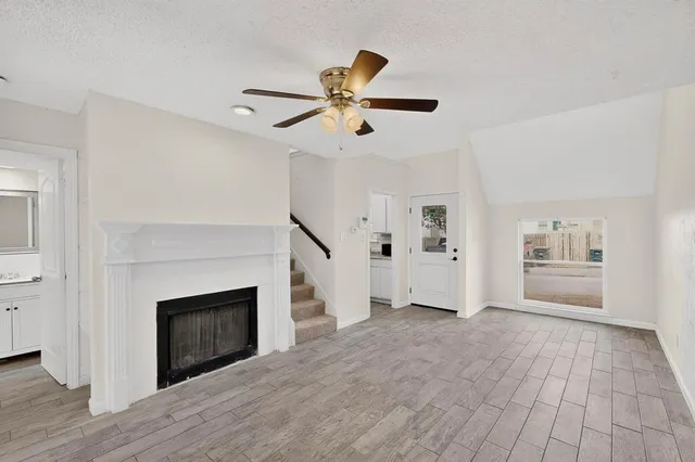 a view of an empty room with a fireplace and a ceiling fan