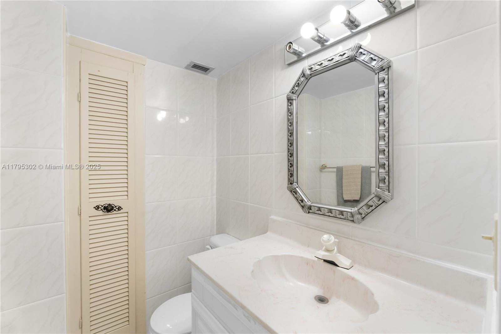 9511 Collins Avenue, Unit 301 Surfside, FL 33154 - Photo 6 of 15 a bathroom with a sink a toilet and a mirror