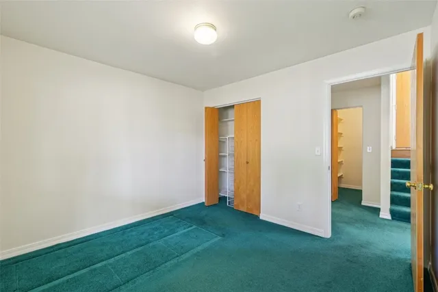 a view of an empty room with closet and wooden floor