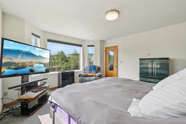 a large bedroom with a bed and a large window with the outer view