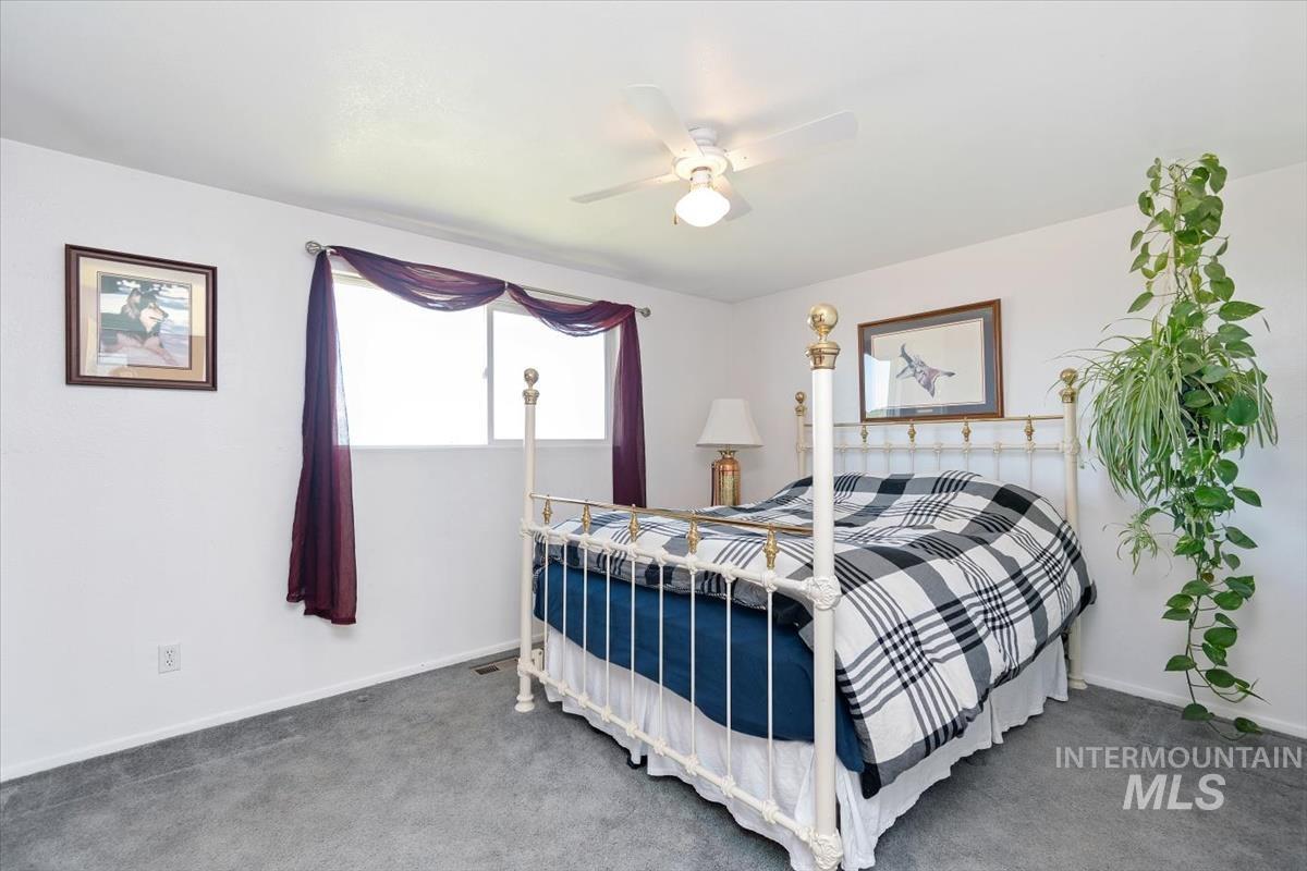 10178 West Fox Ridge Drive Boise, ID 83709 - Photo 14 of 36 Carpeted room featuring a ceiling fan with light fixture, white walls, and a window with dark purple drapery