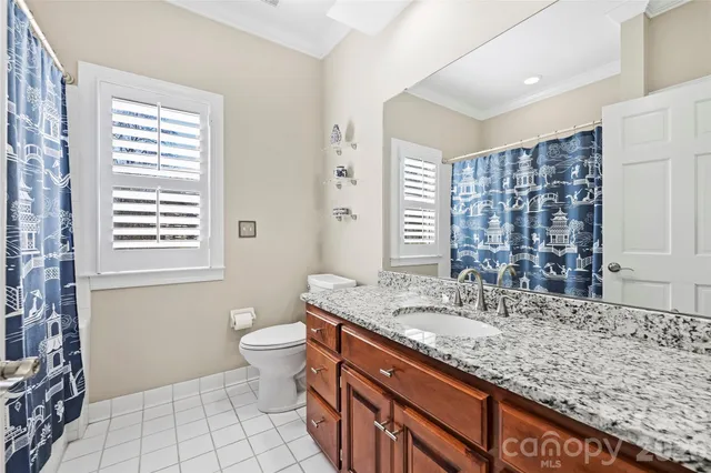 a bathroom with a granite countertop sink a toilet a mirror and shower