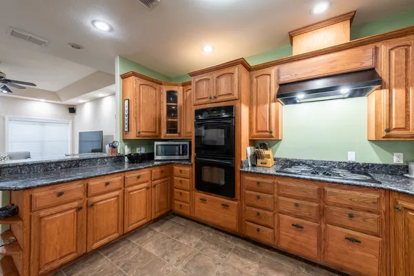 a large kitchen with granite countertop a sink and dishwasher a oven with wooden cabinets