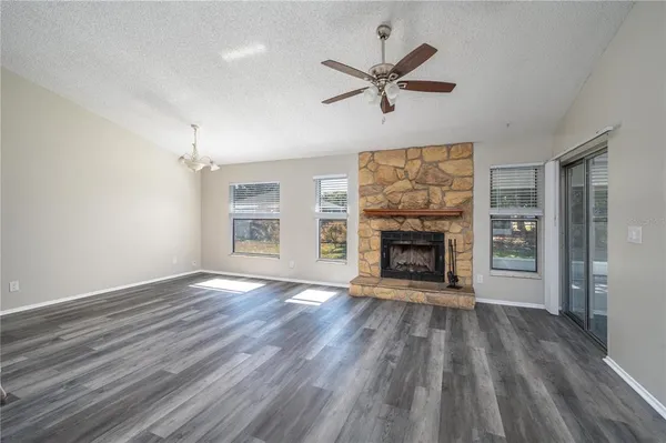 a view of an empty room with wooden floor fireplace and a window