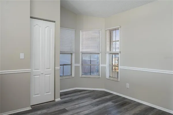 an empty room with wooden floor closet and windows