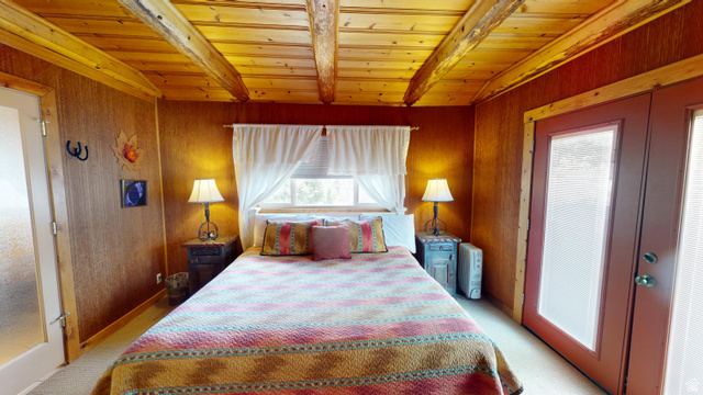 315 Abbey Road Moab, UT 84532 - Photo 27 of 46 Bedroom featuring french doors, light colored carpet, wooden walls, and wood ceiling