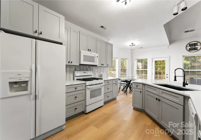 a kitchen with stainless steel appliances white cabinets a sink a stove a refrigerator and white cabinets