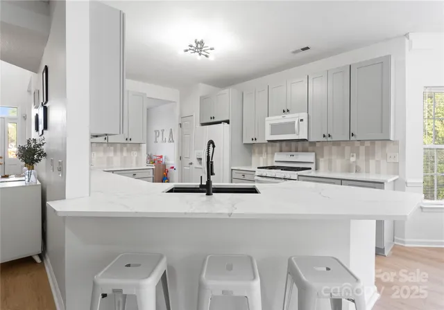 a kitchen with stainless steel appliances a sink a stove a refrigerator cabinets and a window