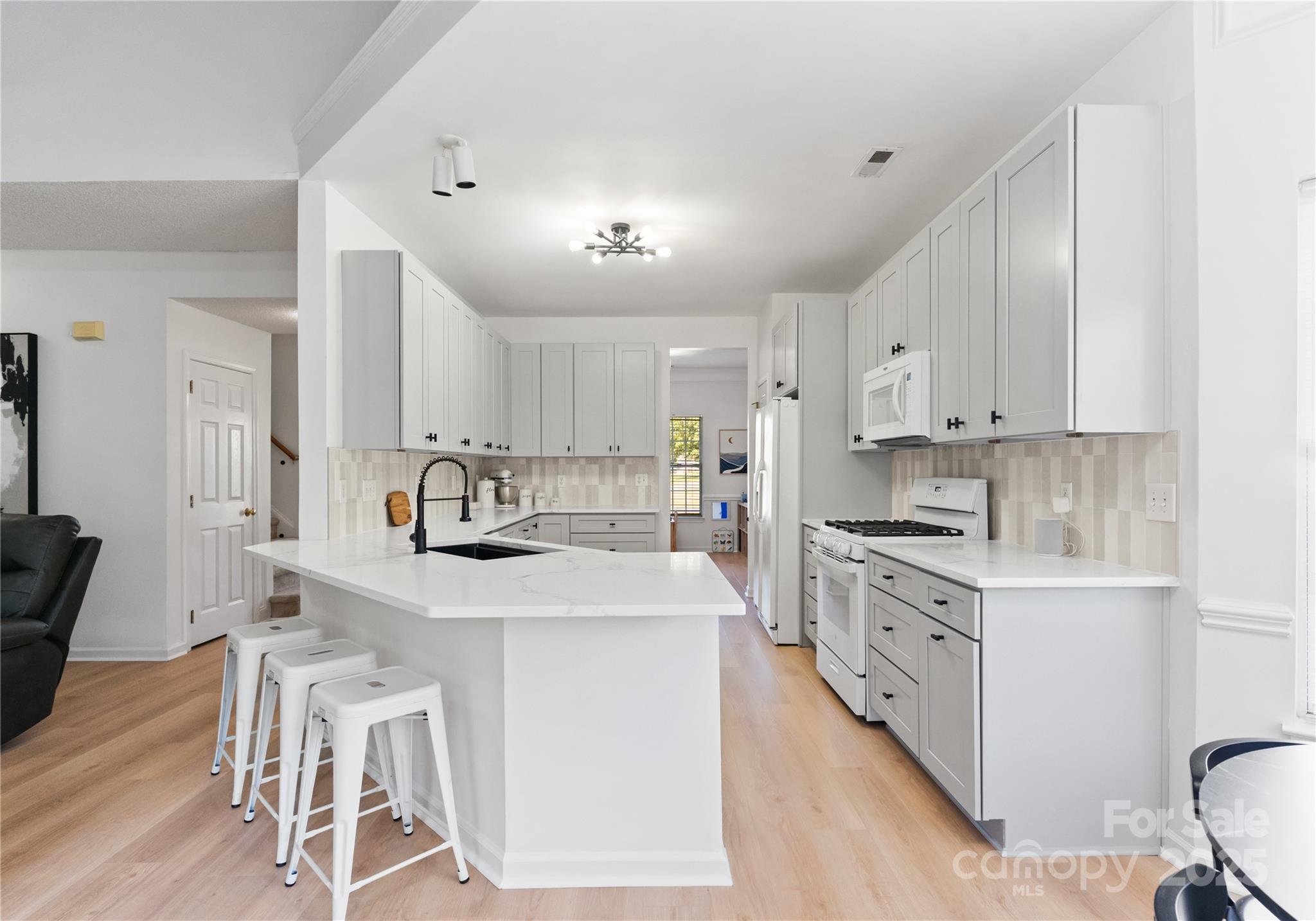 11403 Ridge Oak Drive Charlotte, NC 28273 - Photo 8 of 45 a kitchen with stainless steel appliances kitchen island granite countertop a stove a sink a refrigerator and white cabinets with wooden floor
