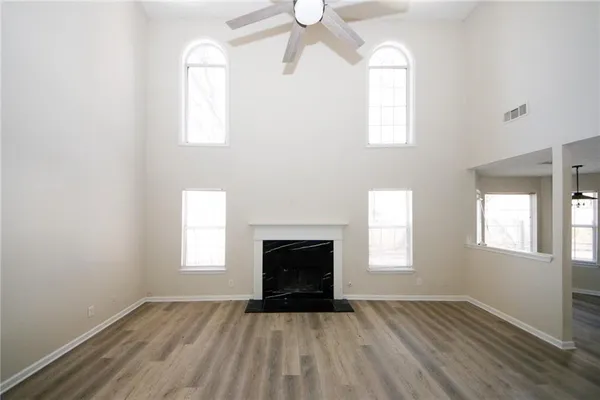 an empty room with wooden floor windows and fireplace