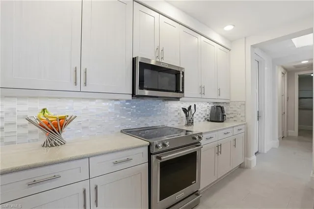 a kitchen with stainless steel appliances granite countertop a refrigerator a sink a stove and white cabinets