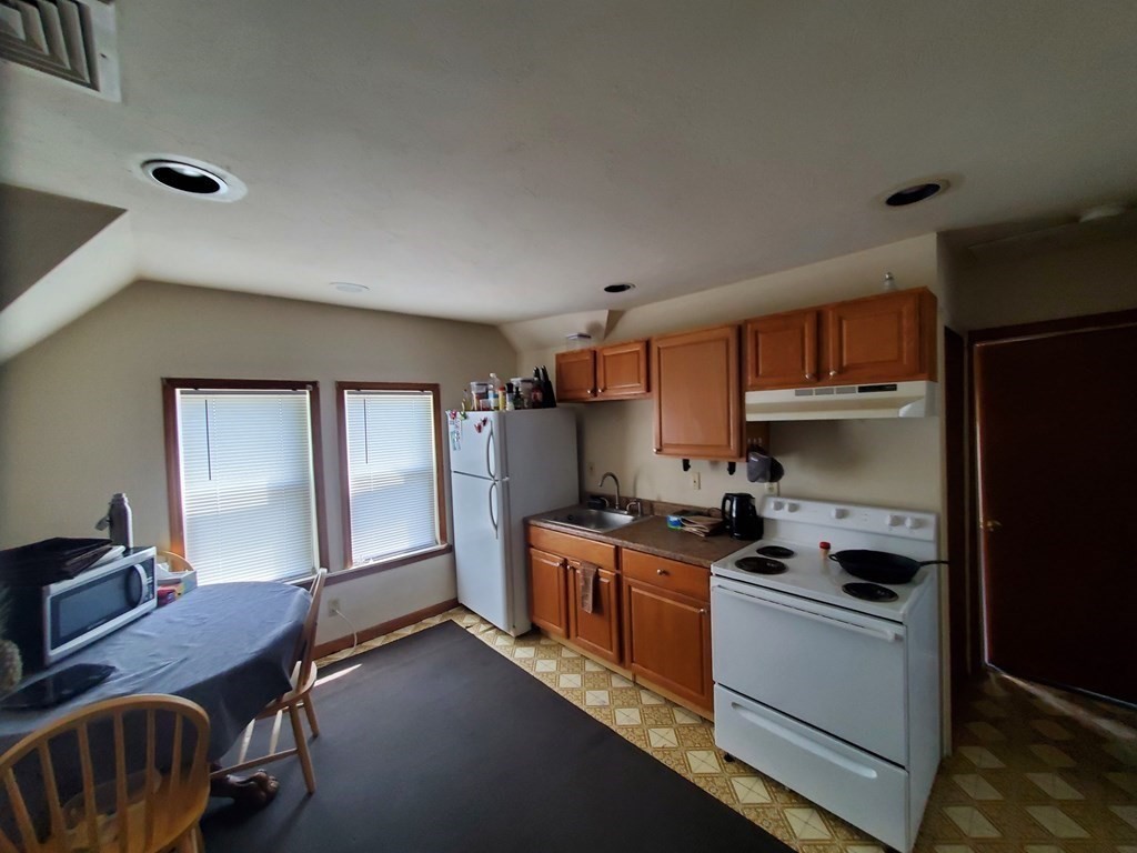 46 Tatman Street Worcester, MA 01607 - Photo 25 of 31 a kitchen with stainless steel appliances a stove a sink dishwasher a refrigerator white cabinets and wooden floor