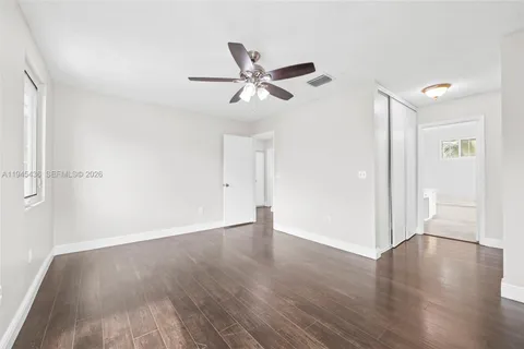 an empty room with wooden floor ceiling fan and windows