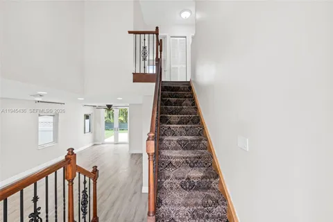a view of a hallway with wooden floor and stairs
