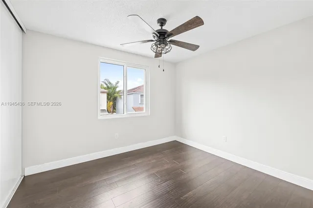 an empty room with wooden floor ceiling fan and windows