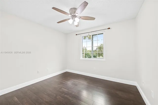 an empty room with wooden floor and ceiling fan