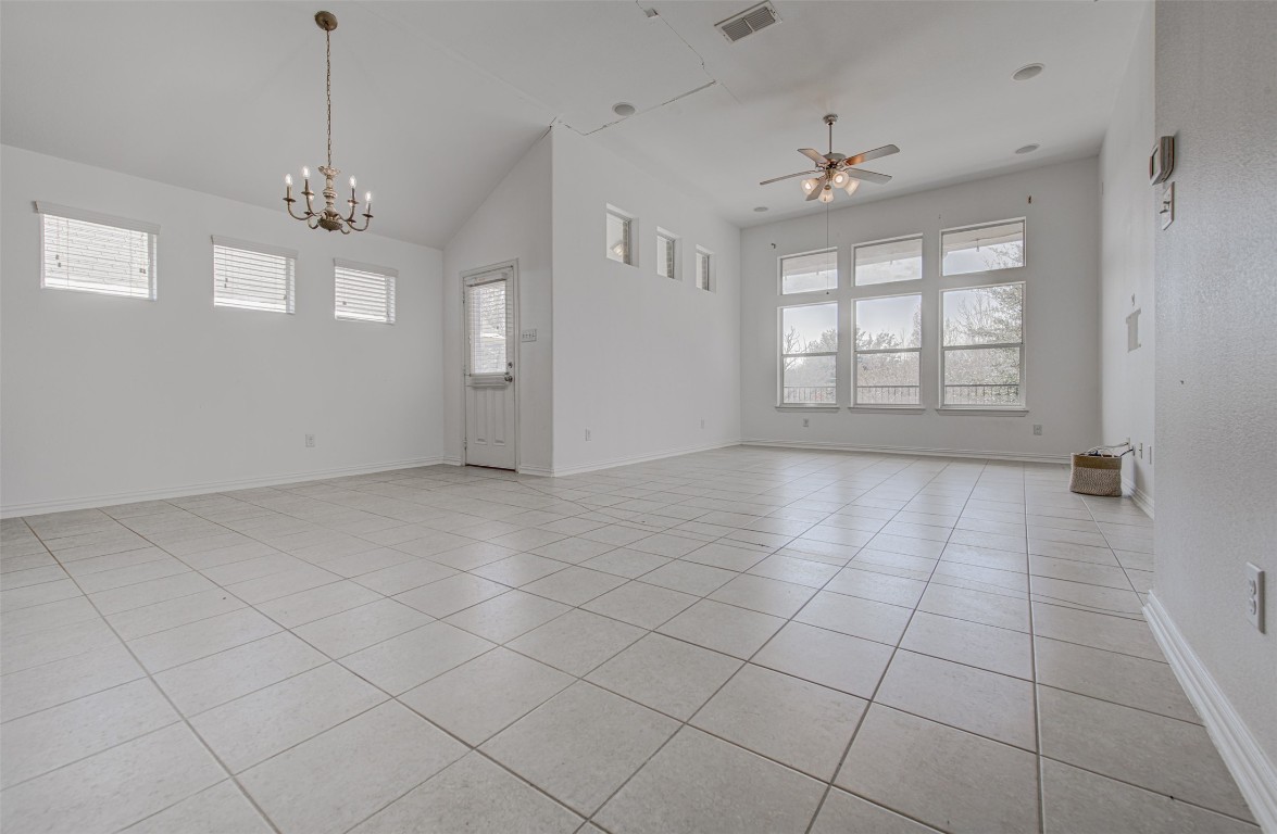 239 Pond View Pass Buda, TX 78610 - Photo 15 of 30 Empty room with ceiling fan, light tile patterned floors, vaulted ceiling, and a chandelier
