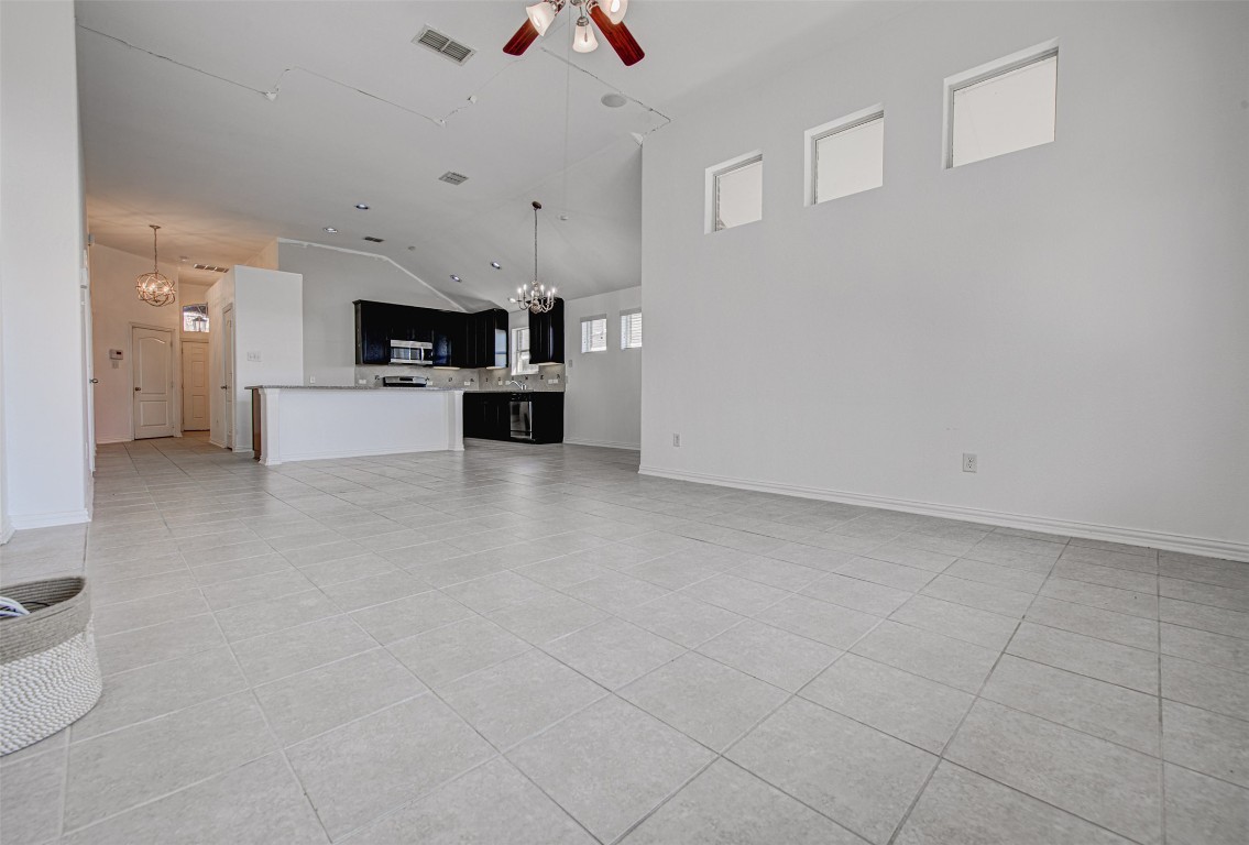239 Pond View Pass Buda, TX 78610 - Photo 16 of 30 Unfurnished living room featuring a chandelier, light tile patterned floors, a ceiling fan, and high vaulted ceiling