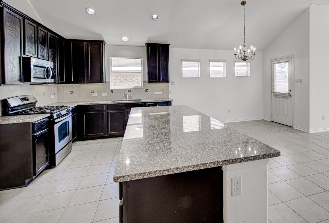 239 Pond View Pass Buda, TX 78610 - Photo 6 of 30 Kitchen with stainless steel appliances, light tile patterned flooring, lofted ceiling, decorative backsplash, and light stone counters