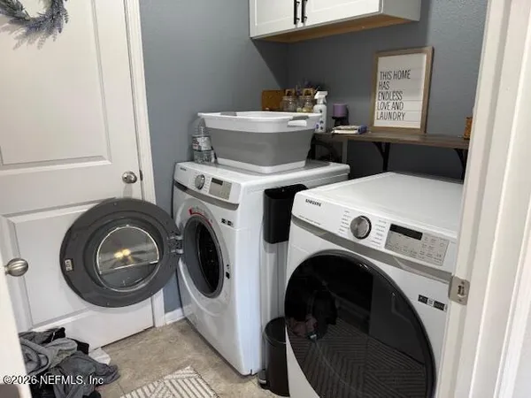 a utility room with dryer washer and a view of kitchen