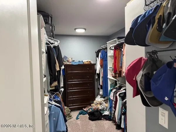 a view of walk in closet with clothes and shoes