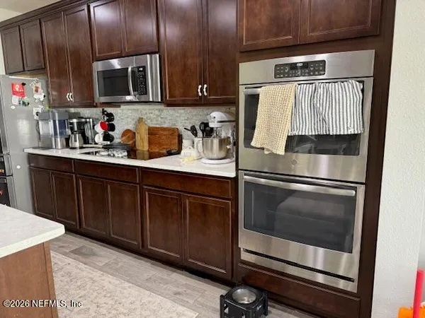 a kitchen with granite countertop wood cabinets stainless steel appliances and a sink