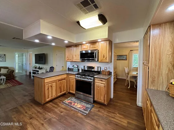 a kitchen with stainless steel appliances granite countertop a stove top oven a sink dishwasher a dining table and chairs with wooden floor