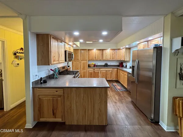 a kitchen with kitchen island a counter top space a sink stainless steel appliances and cabinets
