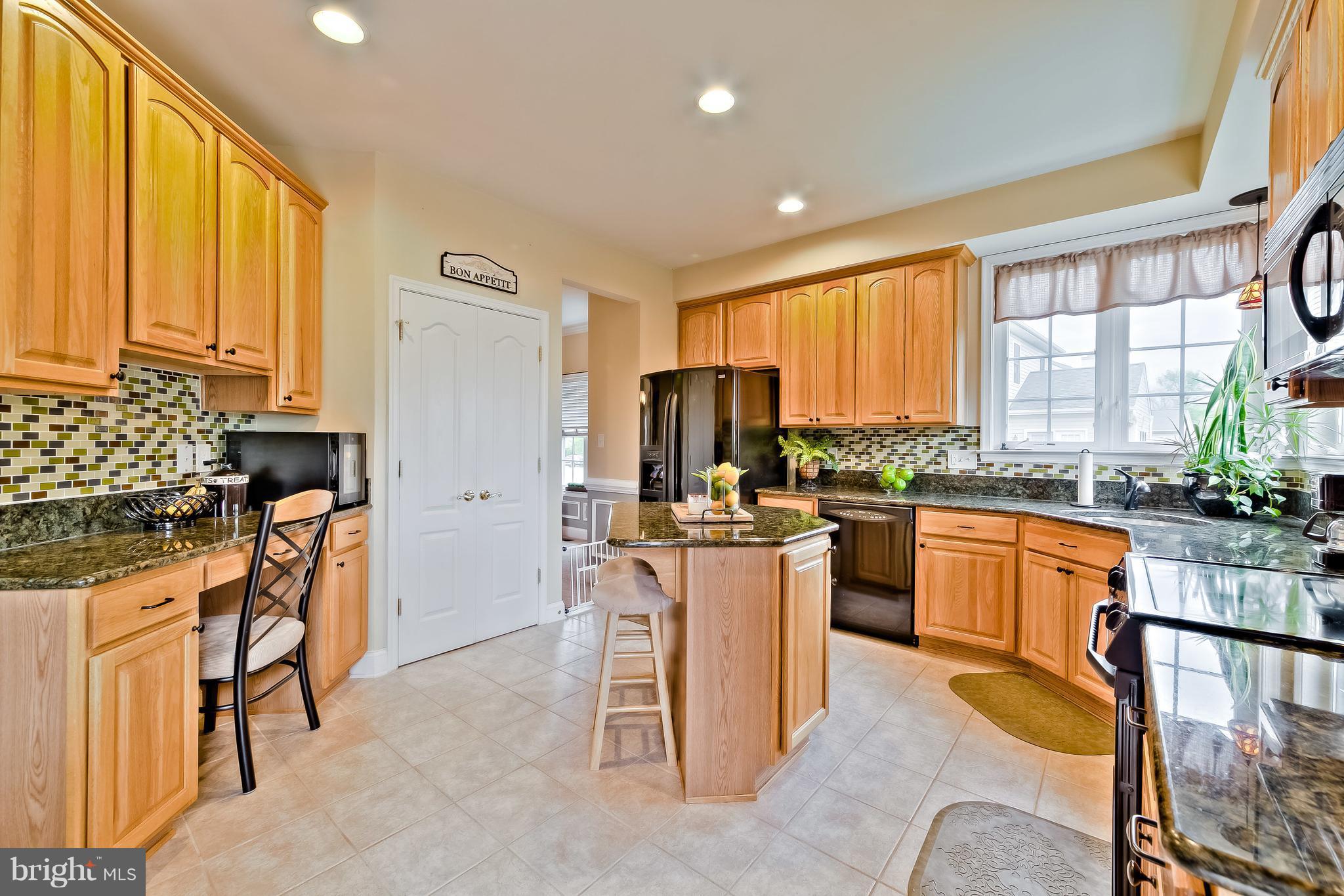 5704 New Forge Road White Marsh, MD 21162 - Photo 12 of 30 a kitchen with stainless steel appliances kitchen island granite countertop a refrigerator a stove top oven a sink dishwasher and wooden cabinets with wooden floor