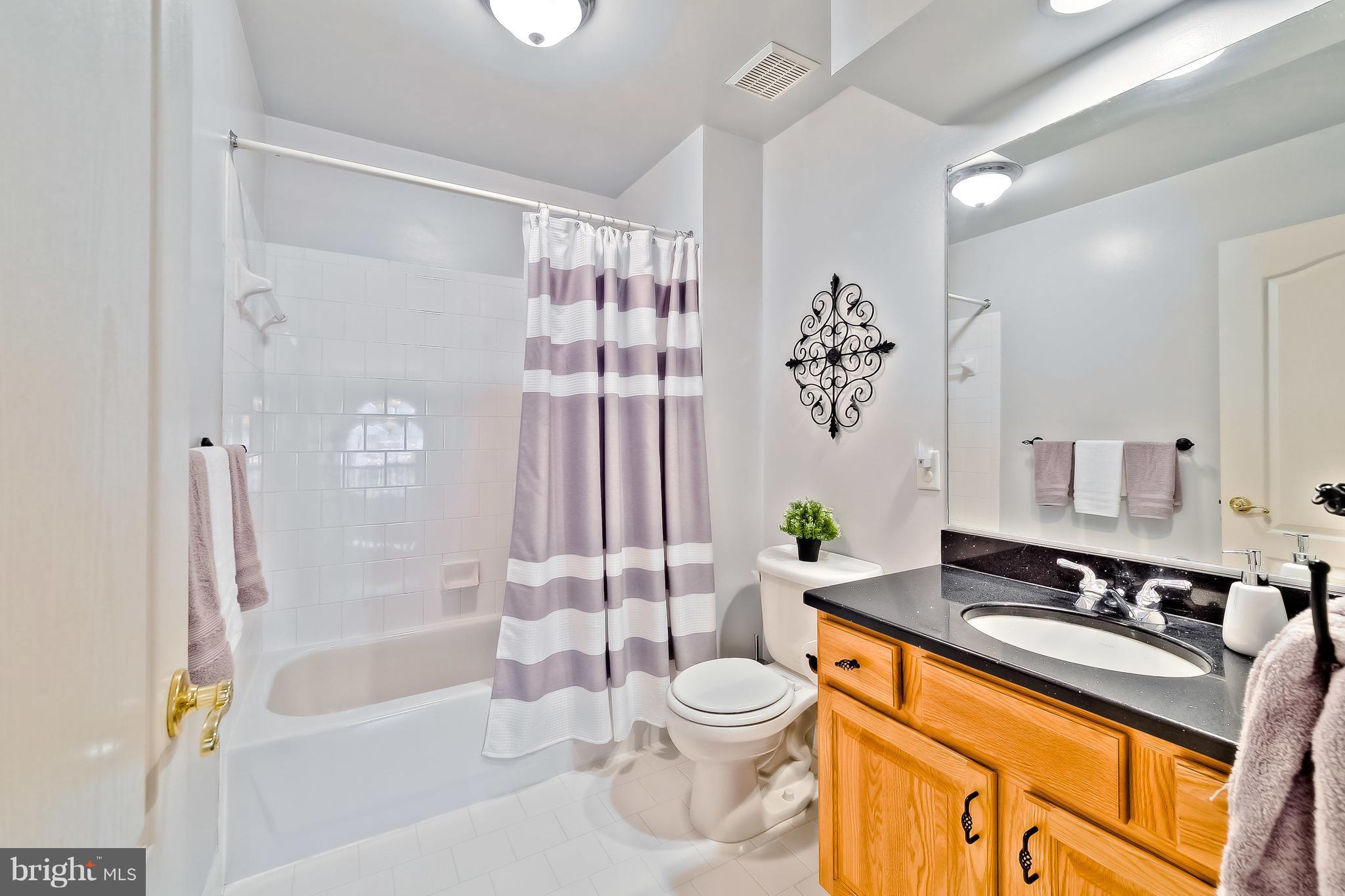 5704 New Forge Road White Marsh, MD 21162 - Photo 18 of 30 a bathroom with a granite countertop sink toilet a mirror a bathtub and shower