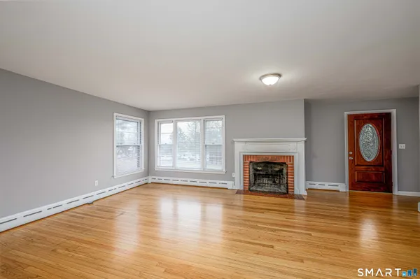 an empty room with fireplace wooden floor and windows