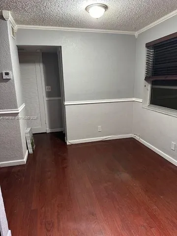 an empty room with wooden floor and window